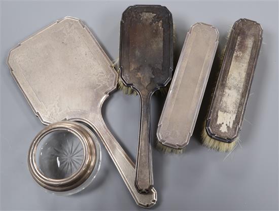 A silver hand mirror, three silver brushes and a toilet jar.